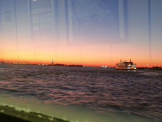 A recent view of the Statue of Liberty at sunset, also with the Staten Island ferry.
