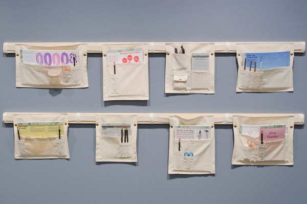 Activities housed in canvas pouches, displayed on a wall. Participants can attach them to garments using the snaps. Supported by a Fellowship from Kala Art Institute and an Artist-in-Residence Workspace Grant from the Center for Book Arts. Photo: Jiajun Wang