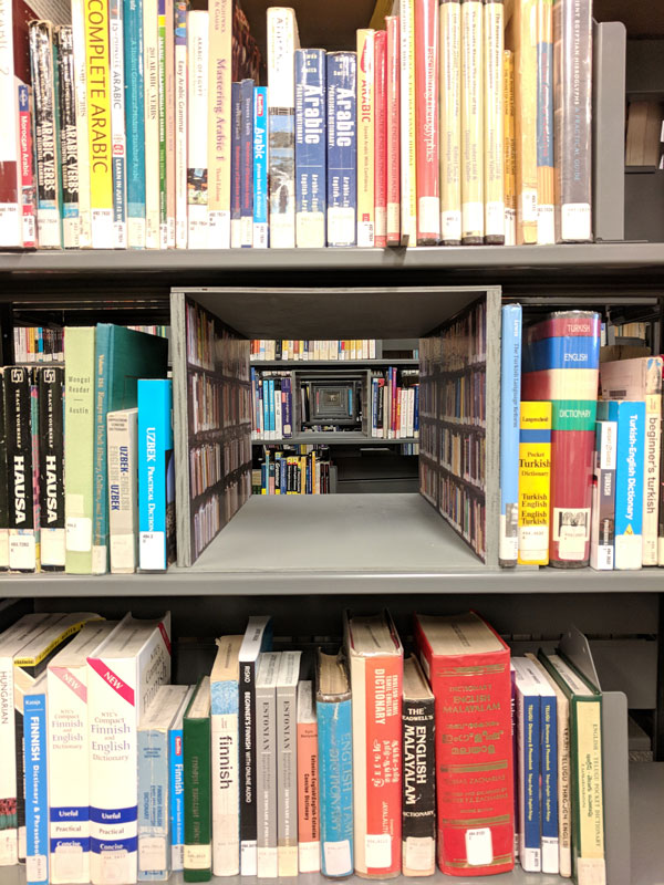 A view of Passage, a portal of perfectly-lined up boxes that create a negative space through the library book shelves.