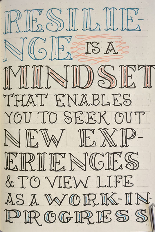 Fancy handlettering on a dot grid sketchbook page in pink, blue and black marker. Text reads: Resilience is a mindset that enables you to seek out new experiences and to view life as a work in progress.