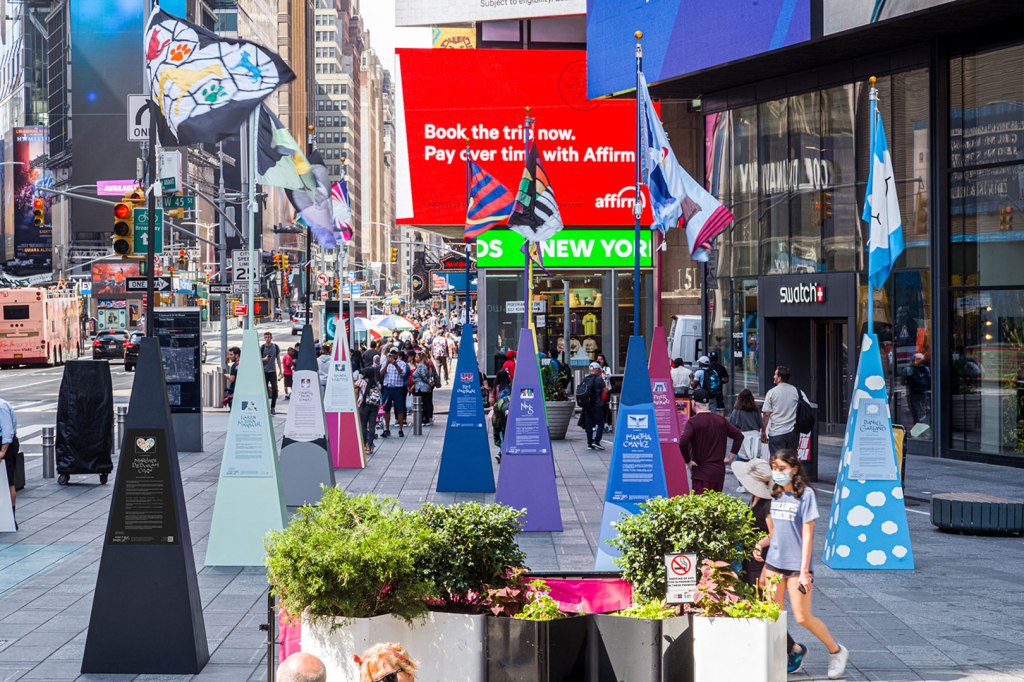 photo of colorful flags flying on matching flag poles with signage on each base. 
